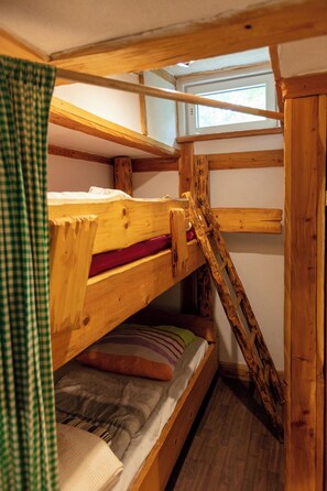 Una cama individual superpuesta con escalera, ventana y cortina.