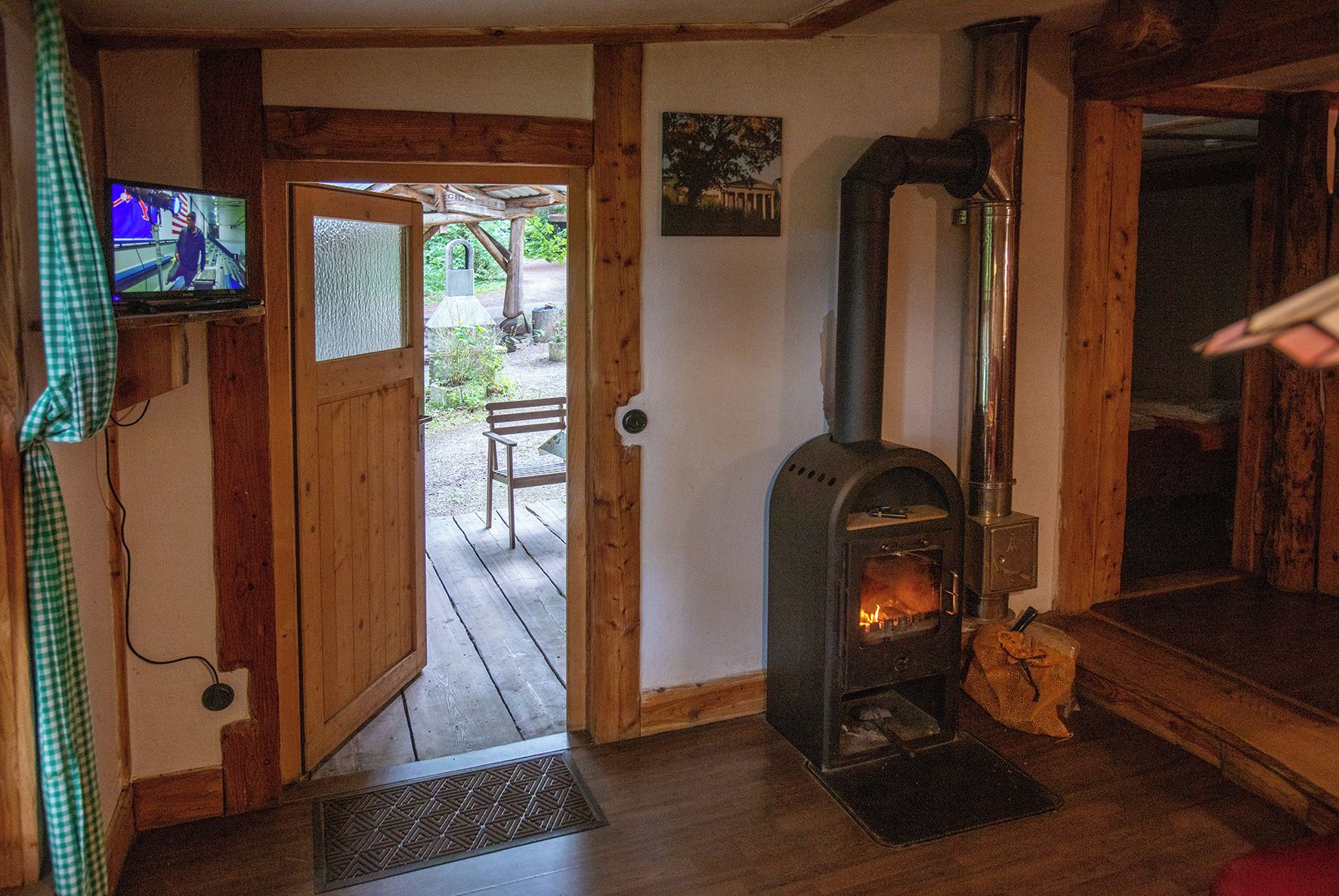 Un interior de madera con chimenea, un televisor y una puerta que da a un espacio exterior.