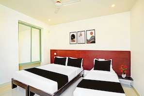 Ein Hotelzimmer mit zwei Betten, einem hölzernen Kopfteil, einem großen Spiegel und drei gerahmten Kunstwerken an der Wand.
