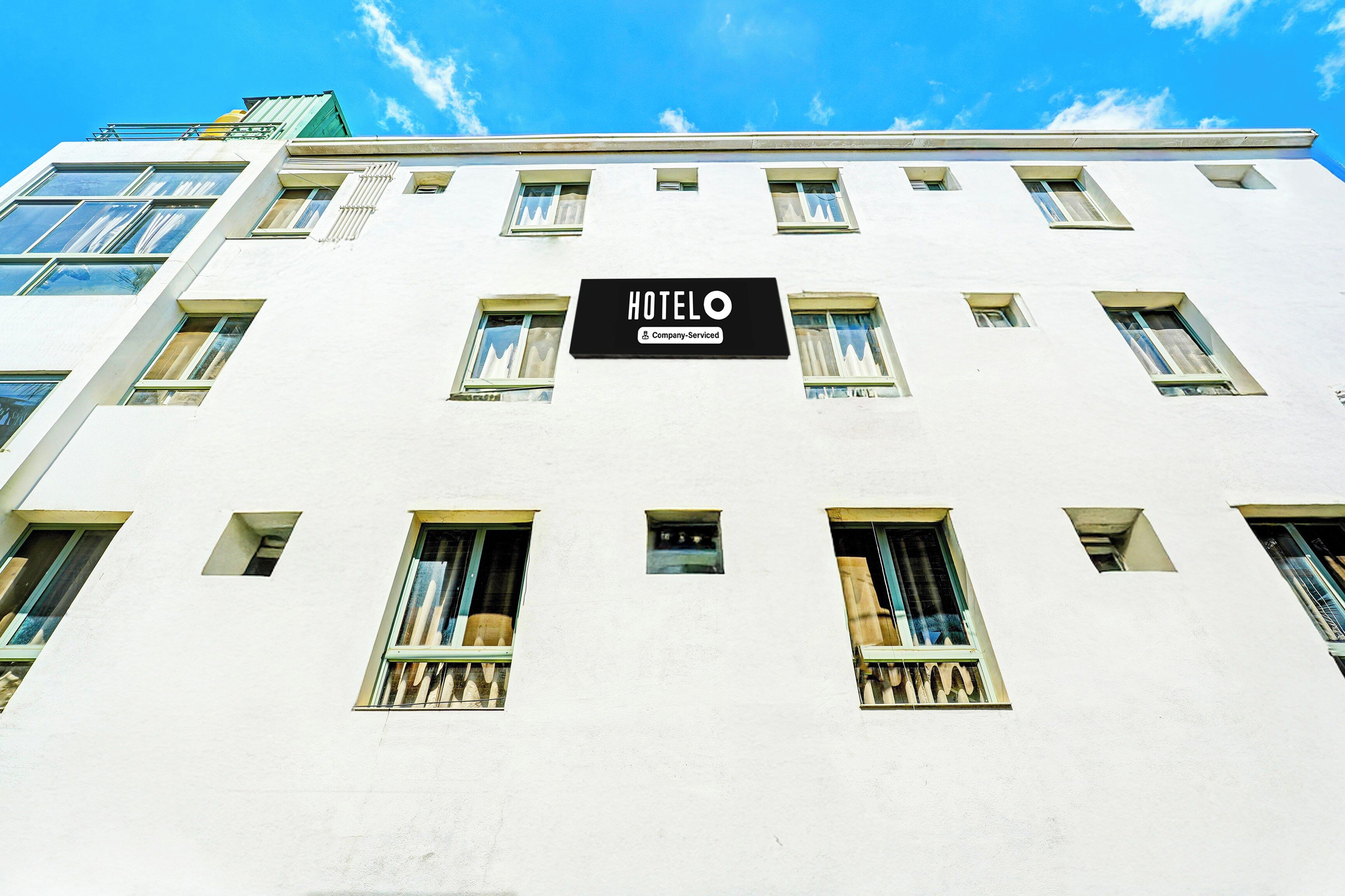 A hotel building with multiple windows and a sign that reads 'HOTEL COMPANY-SERVED'.