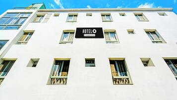 A hotel building with multiple windows and a sign that reads 'HOTEL COMPANY-SERVED'.