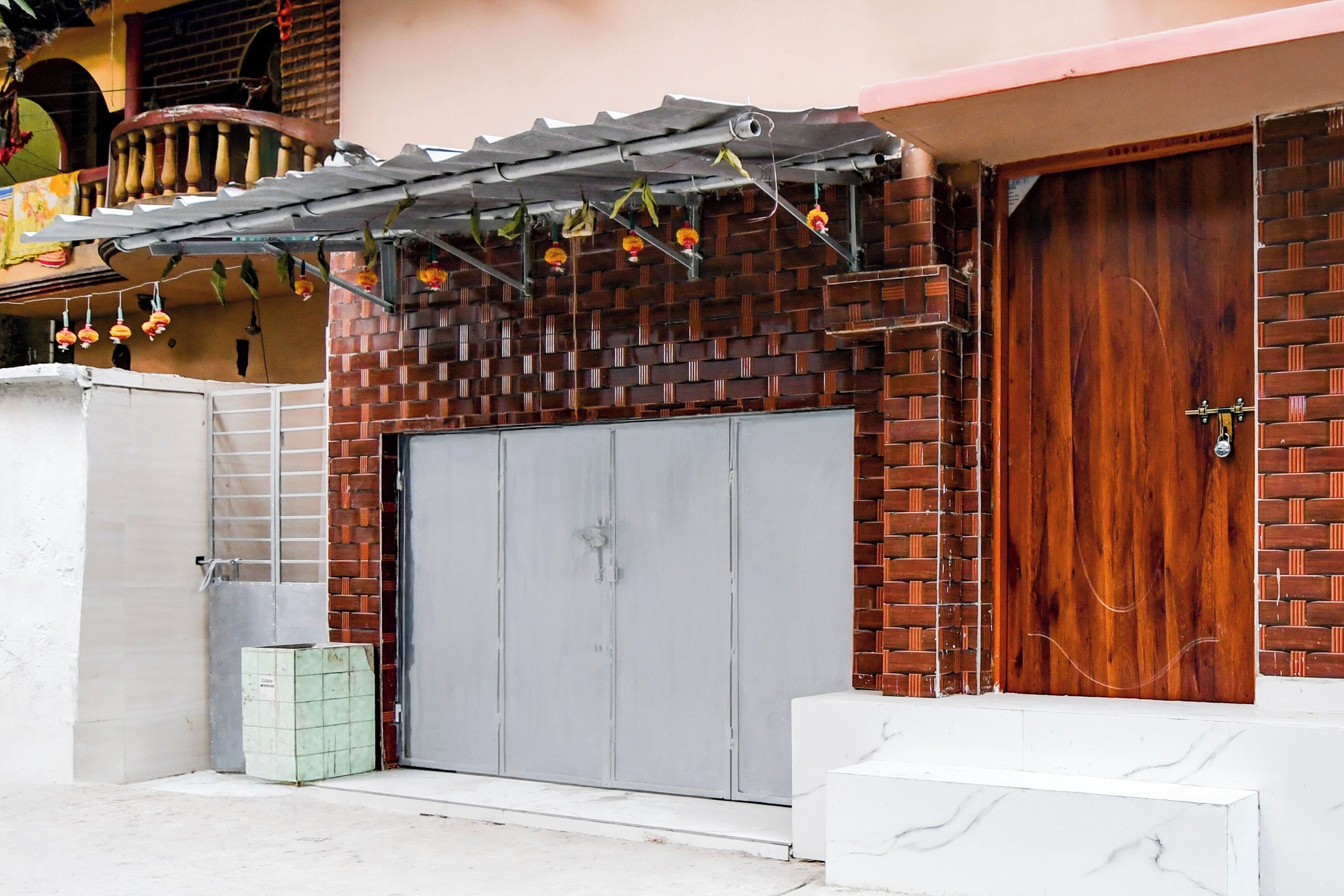 Un edificio con fachada de ladrillo, una puerta doble gris y una puerta de madera.