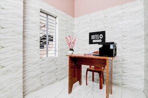Habitación de hotel con pared de mármol, un escritorio de madera, un televisor y un cartel que indica que el servicio de la habitación es proporcionado por la empresa.