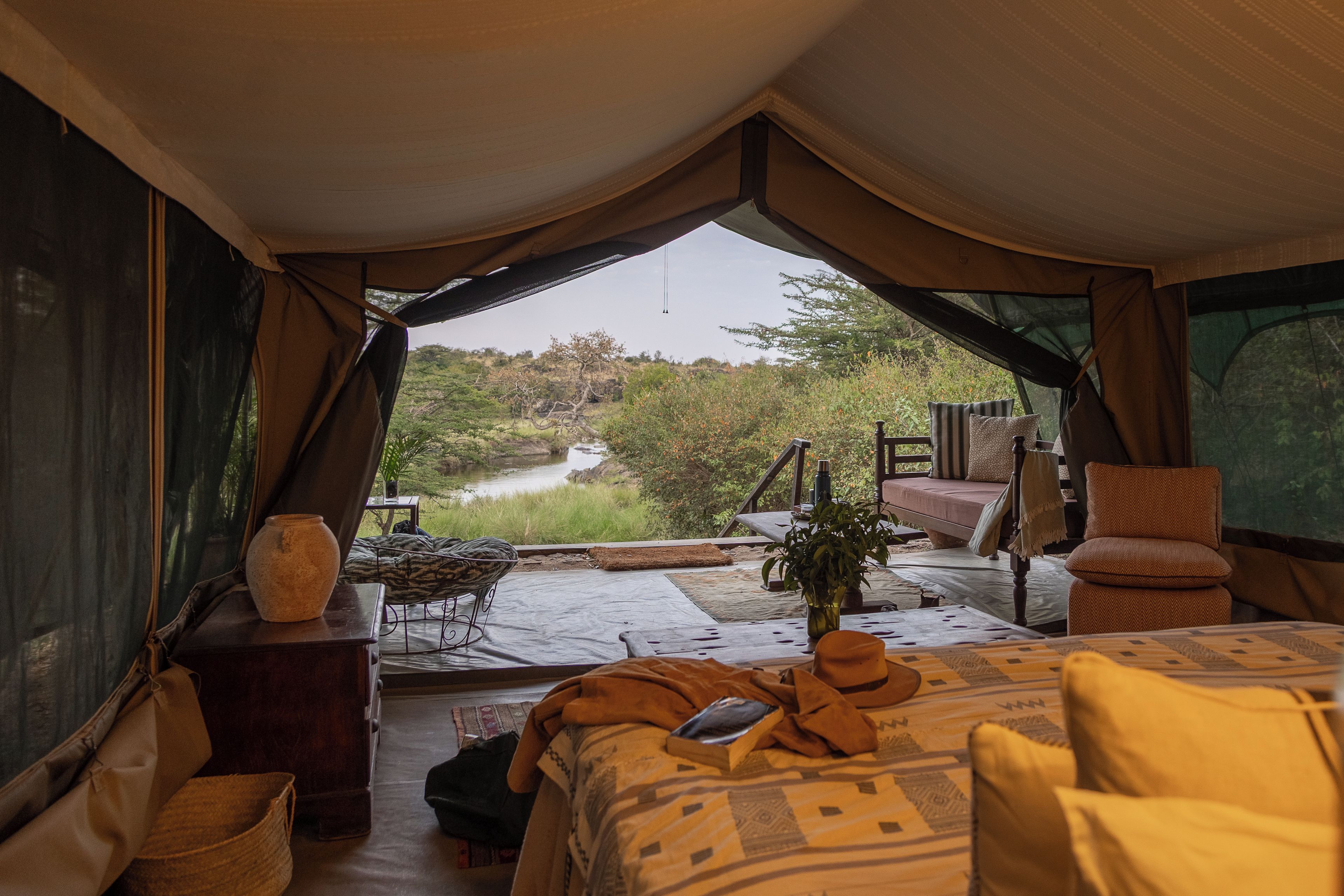 Alojamento em tenda com cama, mesa e vista para um rio.