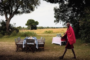An outdoor dining setup with a table and chairs, surrounded by natural scenery.