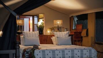 A cozy bedroom with a bed, two bedside lamps, a nightstand, a dresser, and a mirror.