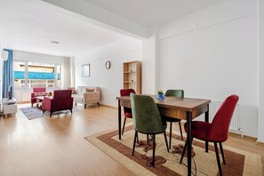 Uma sala de estar moderna com área de jantar, sofá, mesa de centro, estante e vista para o exterior.