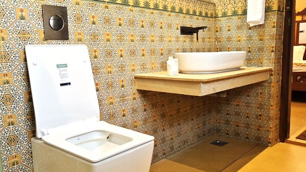 A bathroom with a toilet, a sink, and a shower area. - PL.A Resorts (Thanjavur)