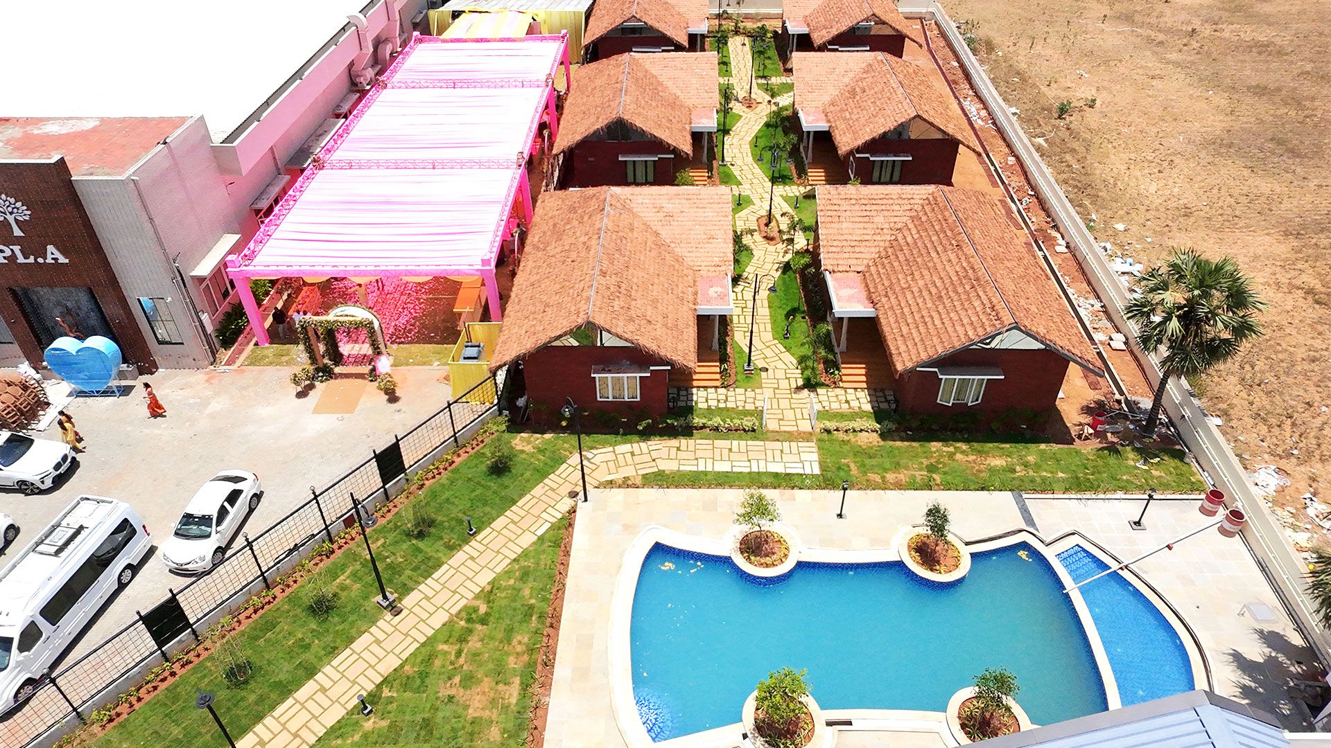 Zona residencial con piscina, varias casas con tejados rojos y un edificio rosa con una gran decoración en forma de corazón.