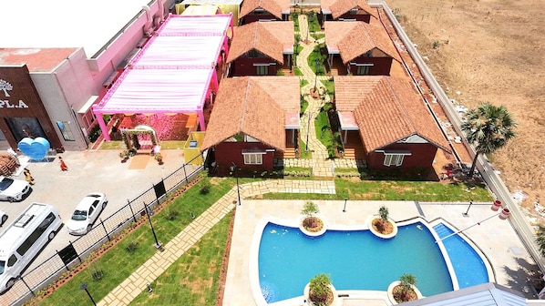 Zona residencial con piscina, varias casas con tejados rojos y un edificio rosa con una gran decoración en forma de corazón.