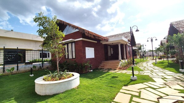 Una casa moderna con césped cuidado, un camino empedrado y un techo de paja.