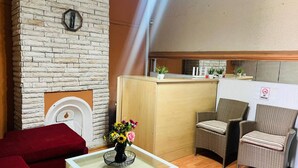 A hotel lobby with a stone fireplace, a reception desk, wicker chairs, and a red sofa. - Adam's central stay in Saltriver Cape Town (Cape Town)