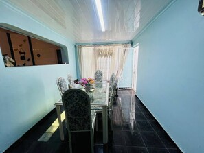 A dining area with a table and chairs, a window with curtains, and a tiled floor.
