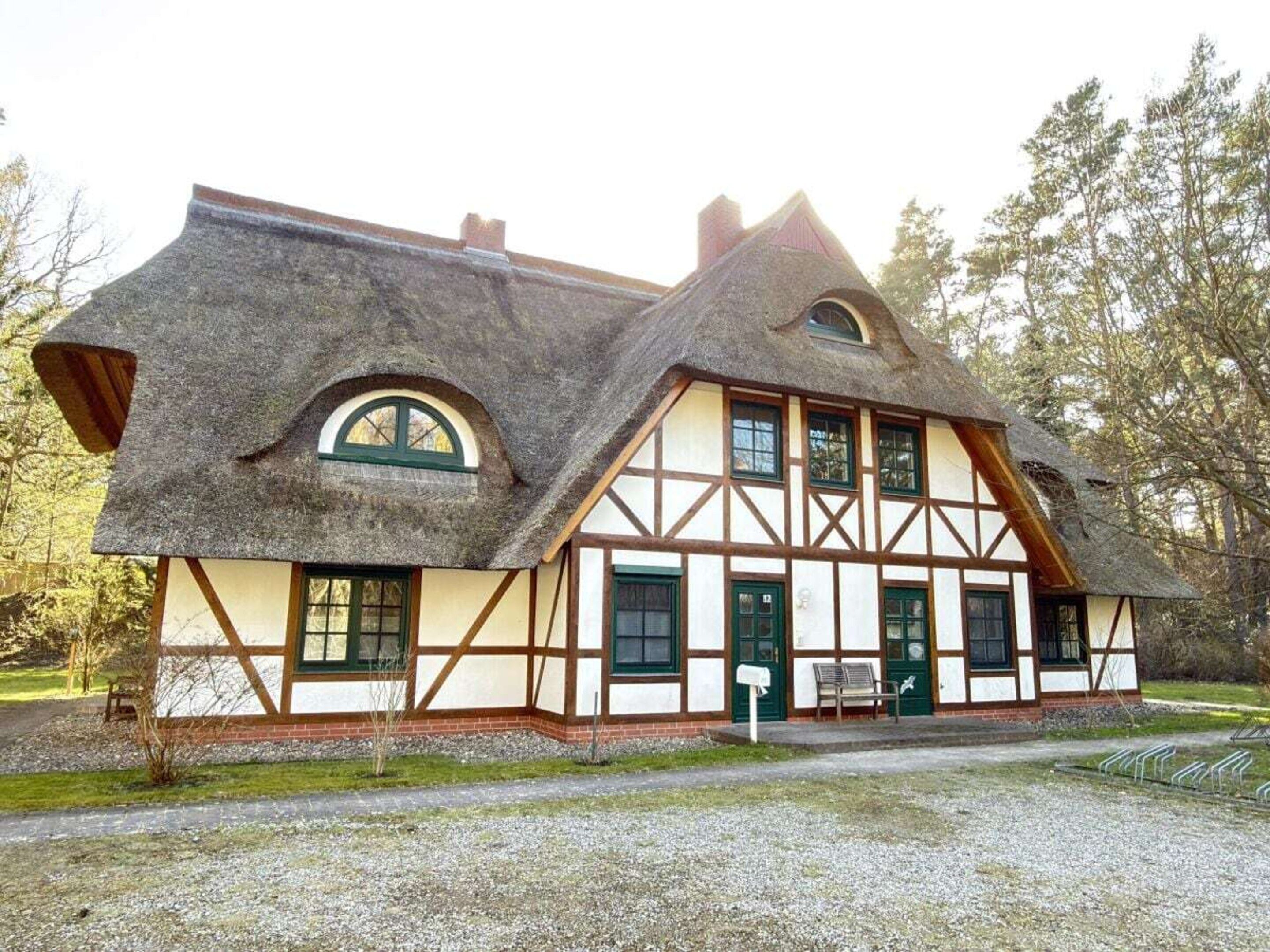 A traditional half-timbered house with a steeply pitched roof, multiple windows, and a small porch area.