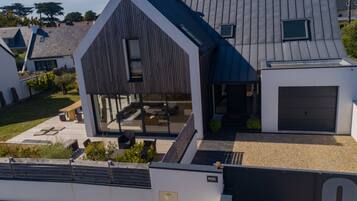 A modern house with a large garage, a covered outdoor seating area, and a well-maintained garden.