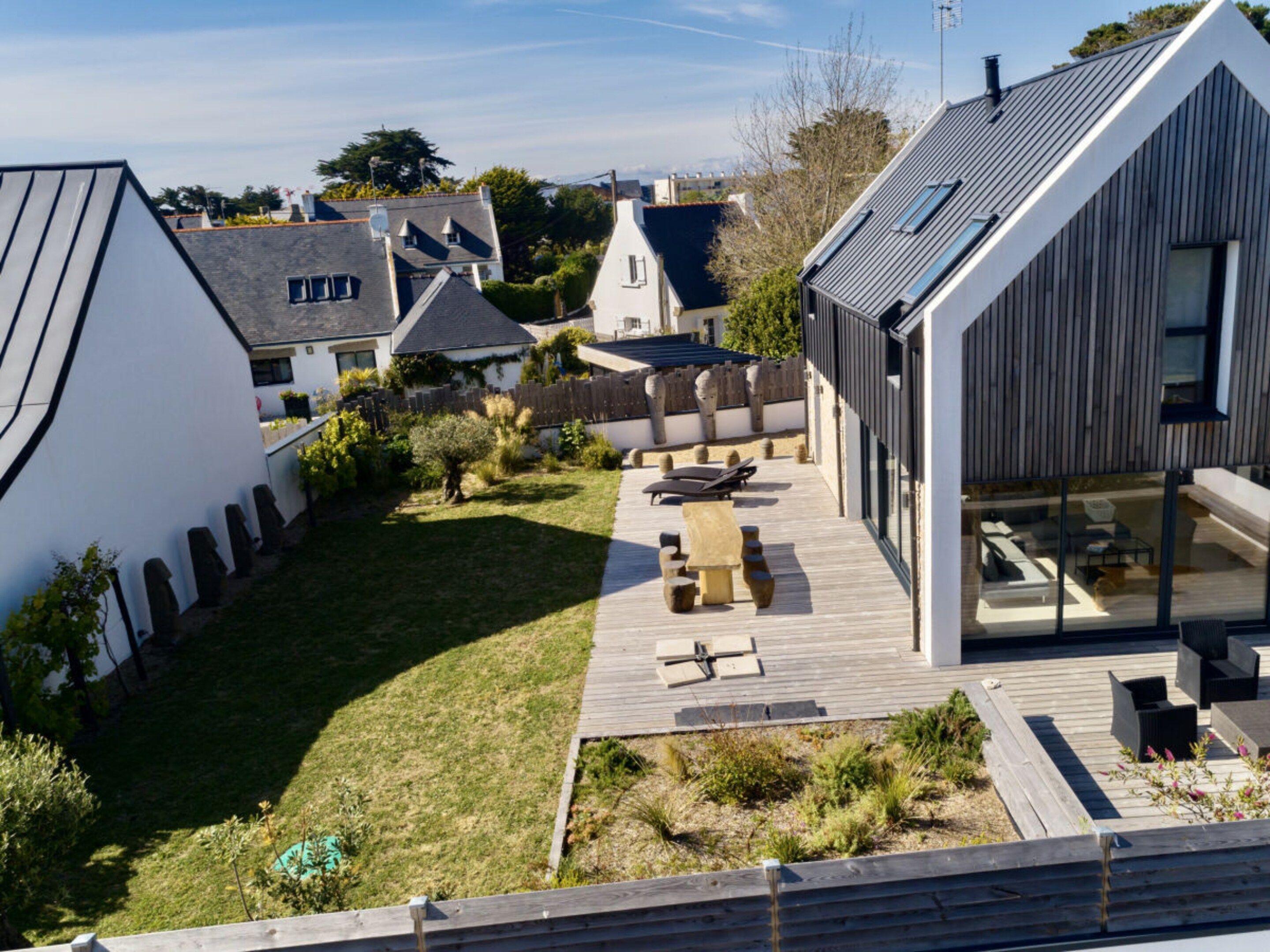 A modern house with a wooden deck, a swimming pool, and a garden.