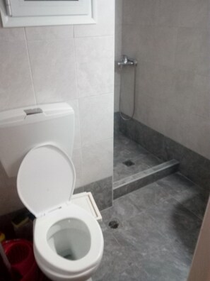 A bathroom with a toilet, a shower, and a tiled floor. - 2-brd cozy home Thessaloniki (Thessaloniki)