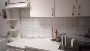 Uma cozinha com armários brancos, bancada branca e painel de azulejos.