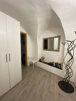Ein Zimmer mit einem weißen Kleiderschrank, einem weißen Sessel, einem Bücherregal, einer sternförmigen Dekoration und einem Spiegel an der Wand.