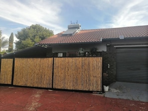 En boligejendom med rødt tegltag, træhegn og garageport.
