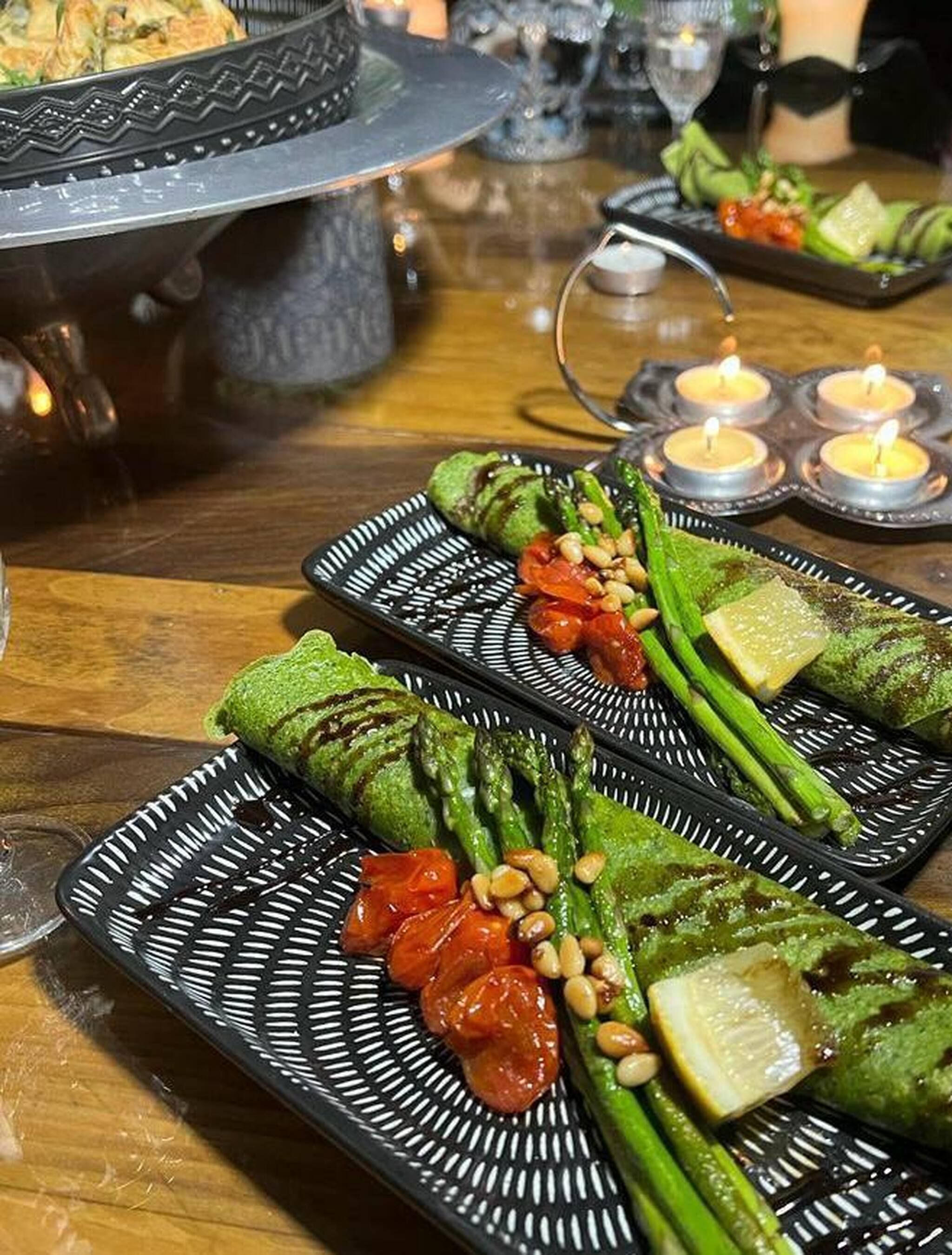 A table set with plates of food, including grilled vegetables and a dish with a patterned design.