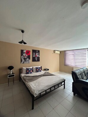 A bedroom with a bed, a nightstand, a lamp, a window with blinds, and wall art. - No 19 suite pendik otel 2 (Pendik)