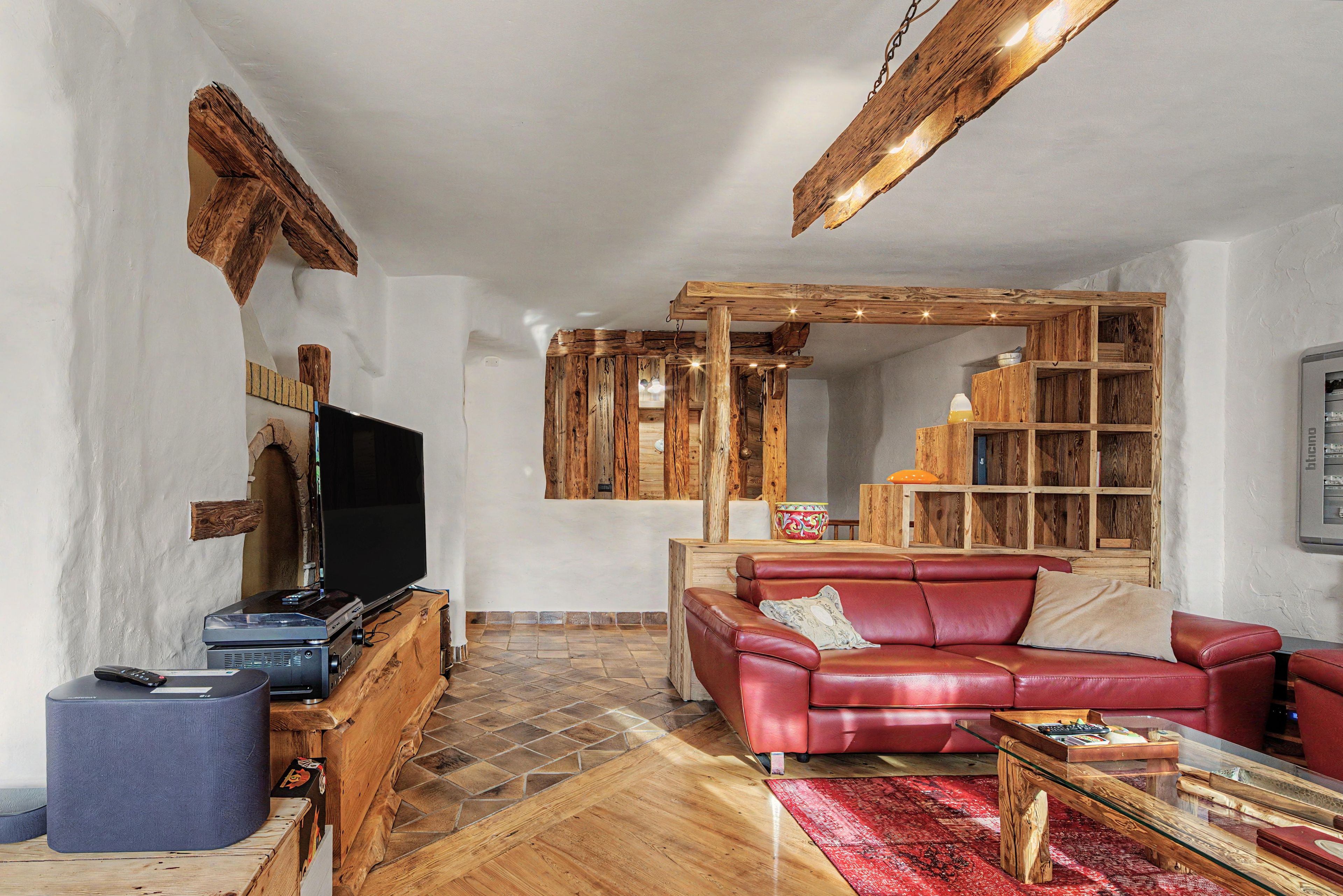 Un salon avec un canapé en cuir rouge, un téléviseur et des meubles en bois.