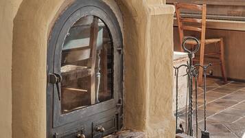 Eine rustikale Holztür mit Metallbeschlag und kleinem Fenster, in eine beige Wand mit Steinboden eingelassen.