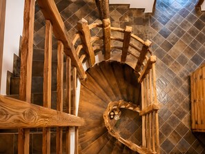 A spiral staircase with wooden railings and a herringbone tile floor.
