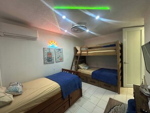 A room with bunk beds, a desk, a chair, and a bed with a blue blanket. - Your dream marina-front getaway is waiting for you (Fajardo city)
