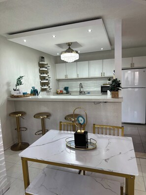 A modern kitchen with white cabinets, a marble countertop, and a chandelier. - Your dream marina-front getaway is waiting for you (Fajardo city)