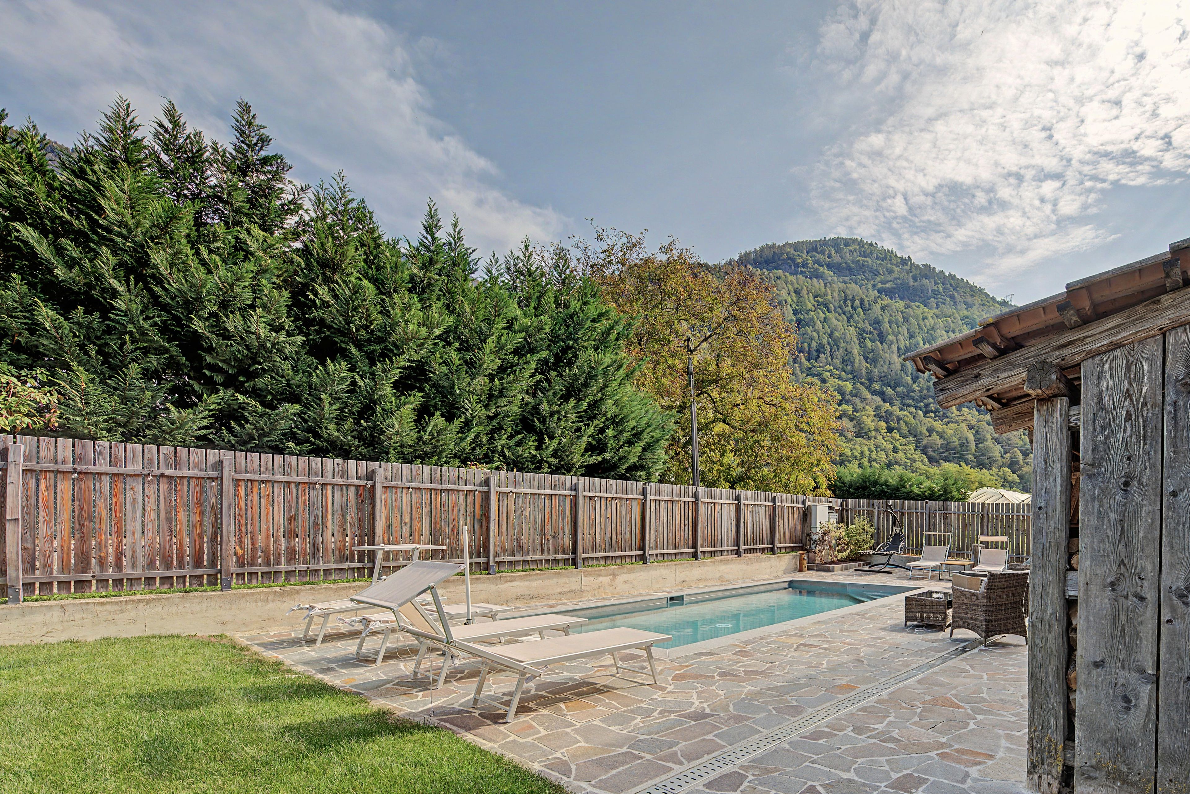 Ein Garten mit Swimmingpool, Liegestühlen und einem Holzzaun.