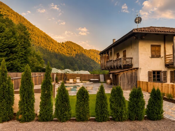 A two-story house with a balcony, a swimming pool, and a wooden fence.