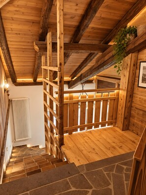 A wooden staircase with stone steps leading to a room with a wooden ceiling and a radiator.