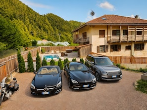 Ein Wohnhaus mit Pool, drei parkenden Autos und Bergblick.