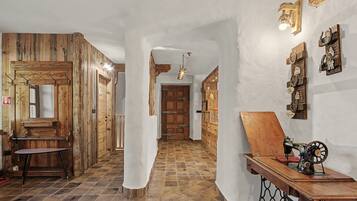 A hallway with wooden walls and doors, a sewing machine on a table, and a light fixture on the wall.