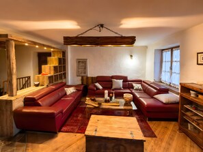Ein Wohnzimmer mit einem roten Ledersofa, einem Holztisch und einem Bücherregal.