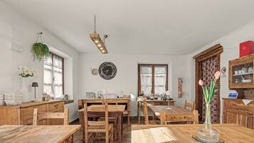 A rustic dining area with wooden furniture, a hanging light fixture, and a wall-mounted clock.