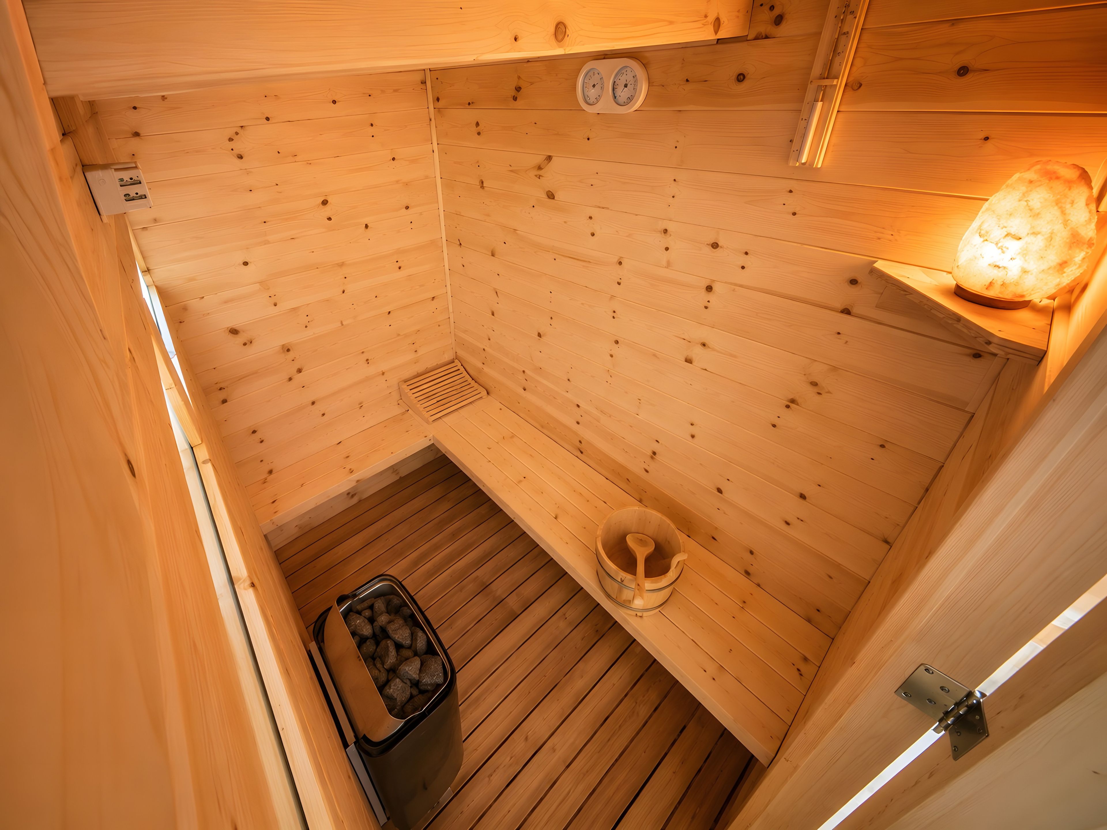 Una sauna in legno con una panca, uno scaldasalviette, un cestino e un piccolo secchio di legno.