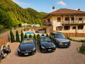 Ein Wohnhaus mit Pool, drei parkenden Autos und Bergblick.