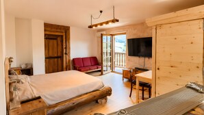 Una stanza in legno con un letto, un divano rosso, una scrivania e un televisore.