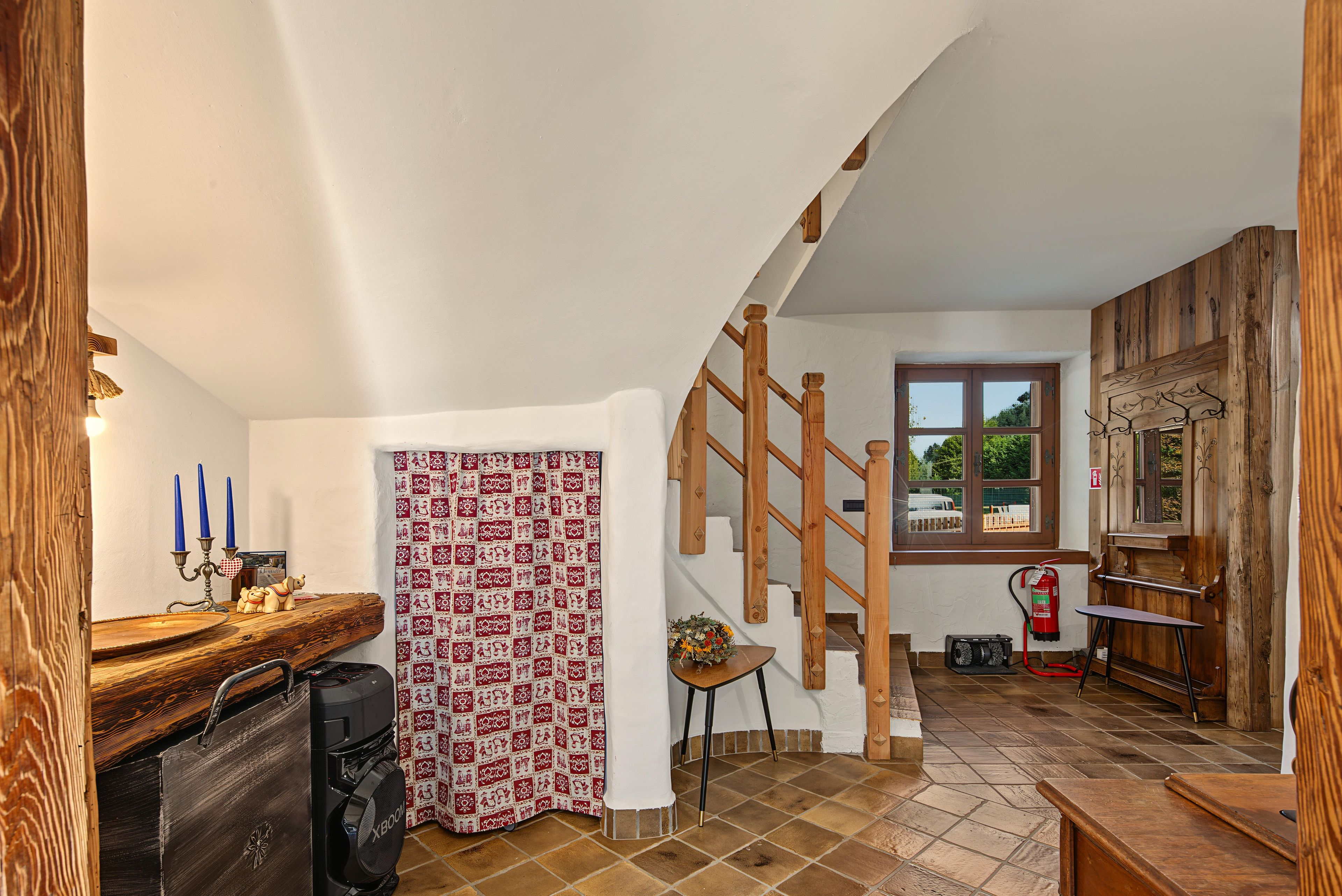 Une pièce avec un escalier en bois, une fenêtre donnant sur un beau paysage et un extincteur fixé au mur.