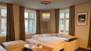A hotel room with a bed, bedside table, and a view of the outside. - Historic Strandgata 36 (Troms)