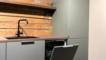 A kitchen with a wooden wall, a sink, and a dishwasher.