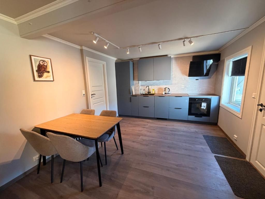 A modern kitchen with grey cabinets, a wooden dining table, and a framed picture on the wall.