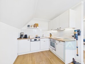Eine moderne Küche mit weißen Schränken, einer Holz Arbeitsplatte, einem eingebauten Backofen und einem Staubsauger.