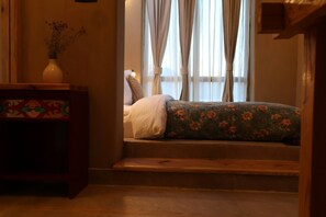 A room with a bed, a wooden bench, and a vase with dried flowers. - Changpa Lodge (Leh)