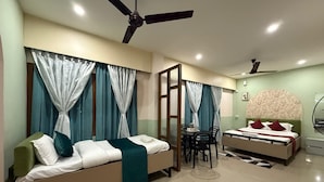 A modern bedroom with a sofa, a bed, a dining table, and two ceiling fans. - Atithi Guest House  (Guwahati)
