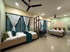 A modern bedroom with a sofa, a bed, a dining table, and two ceiling fans. - Atithi Guest House (Guwahati)