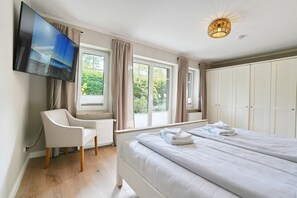 A bedroom with a bed, a chair, a television, and a wardrobe. - La Maison Eichenweg App 1 + 3 - Townhouse on Eichenweg (Scharbeutz)